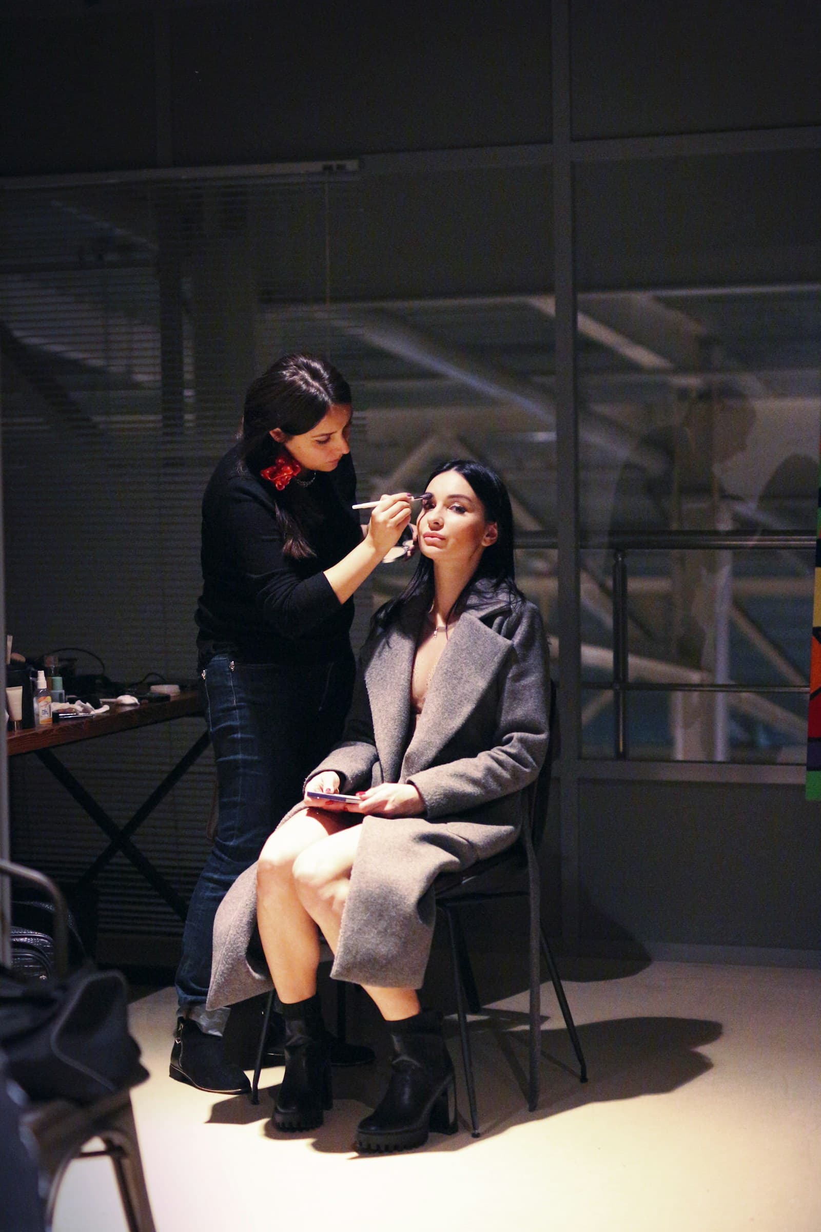 Make-up artist machiind o modelă înainte de tură, în studio
